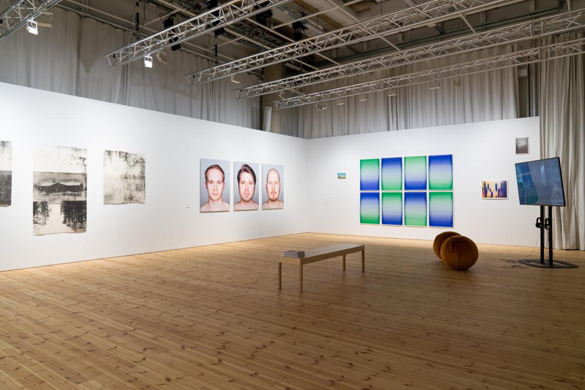 Artworks in a gallery space with wooden floor.